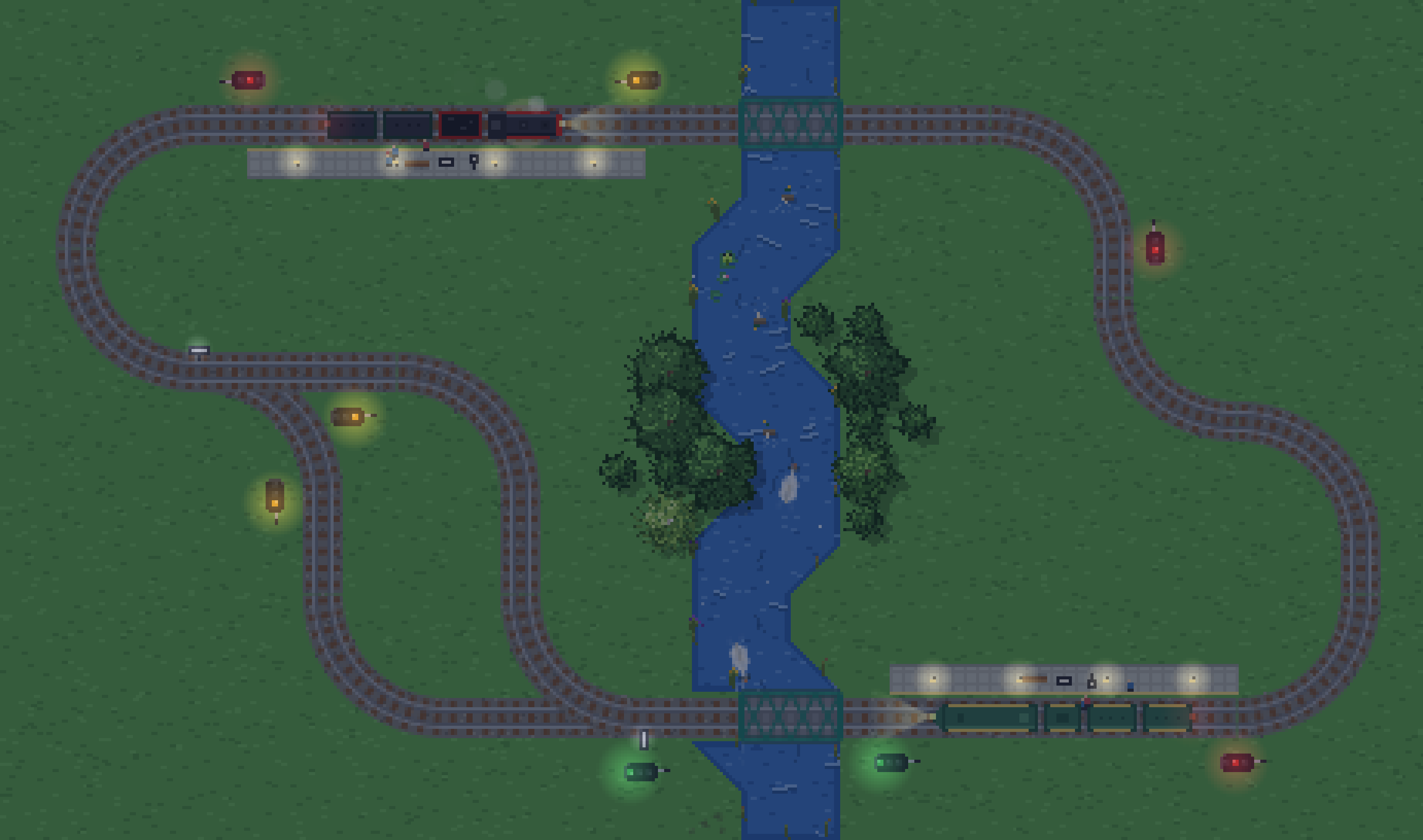 The same circuit at dusk: the grass has gone dark, signal lamps and platform lights glow, and the trains' headlights throw beams down the track.